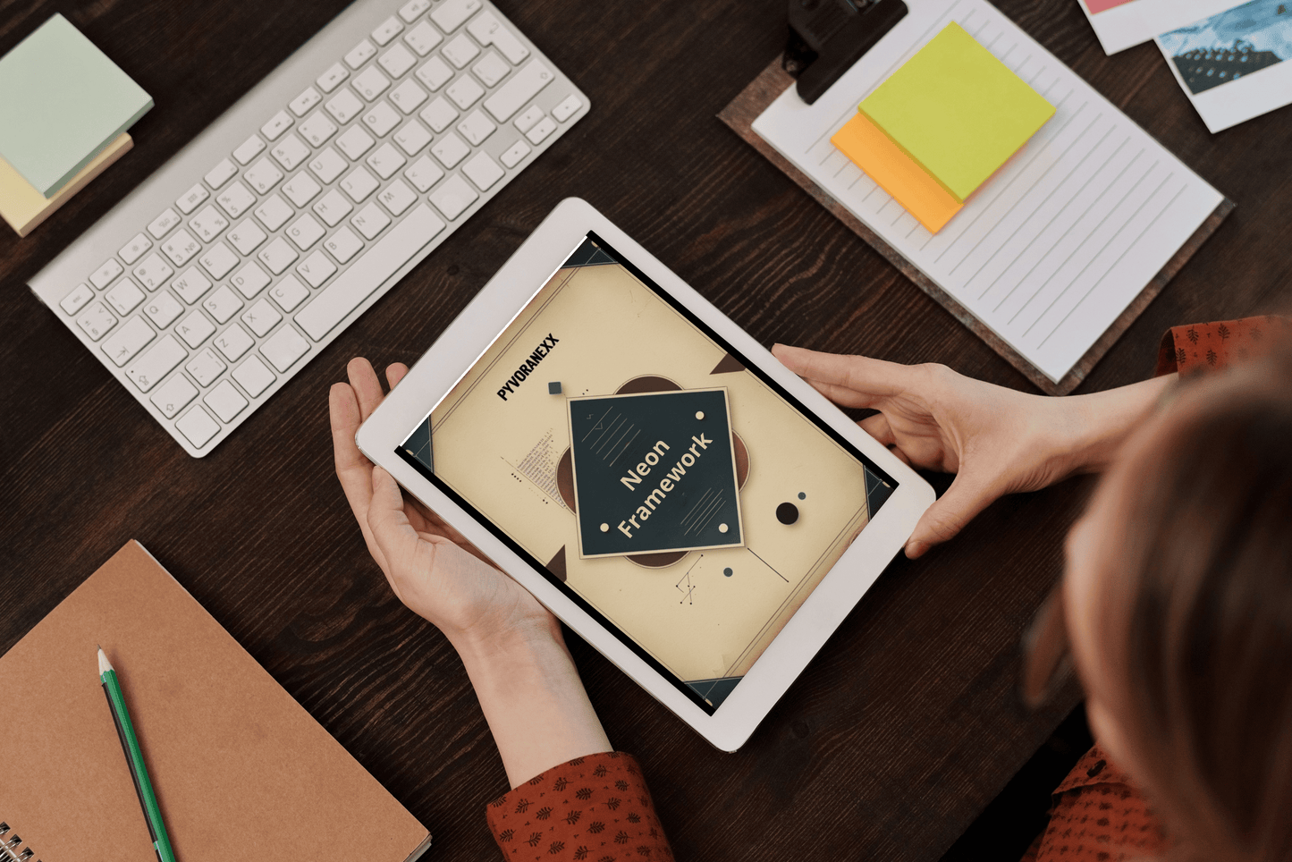 Person holding a tablet with a design Python course open on a desk with a keyboard and stationery items.
