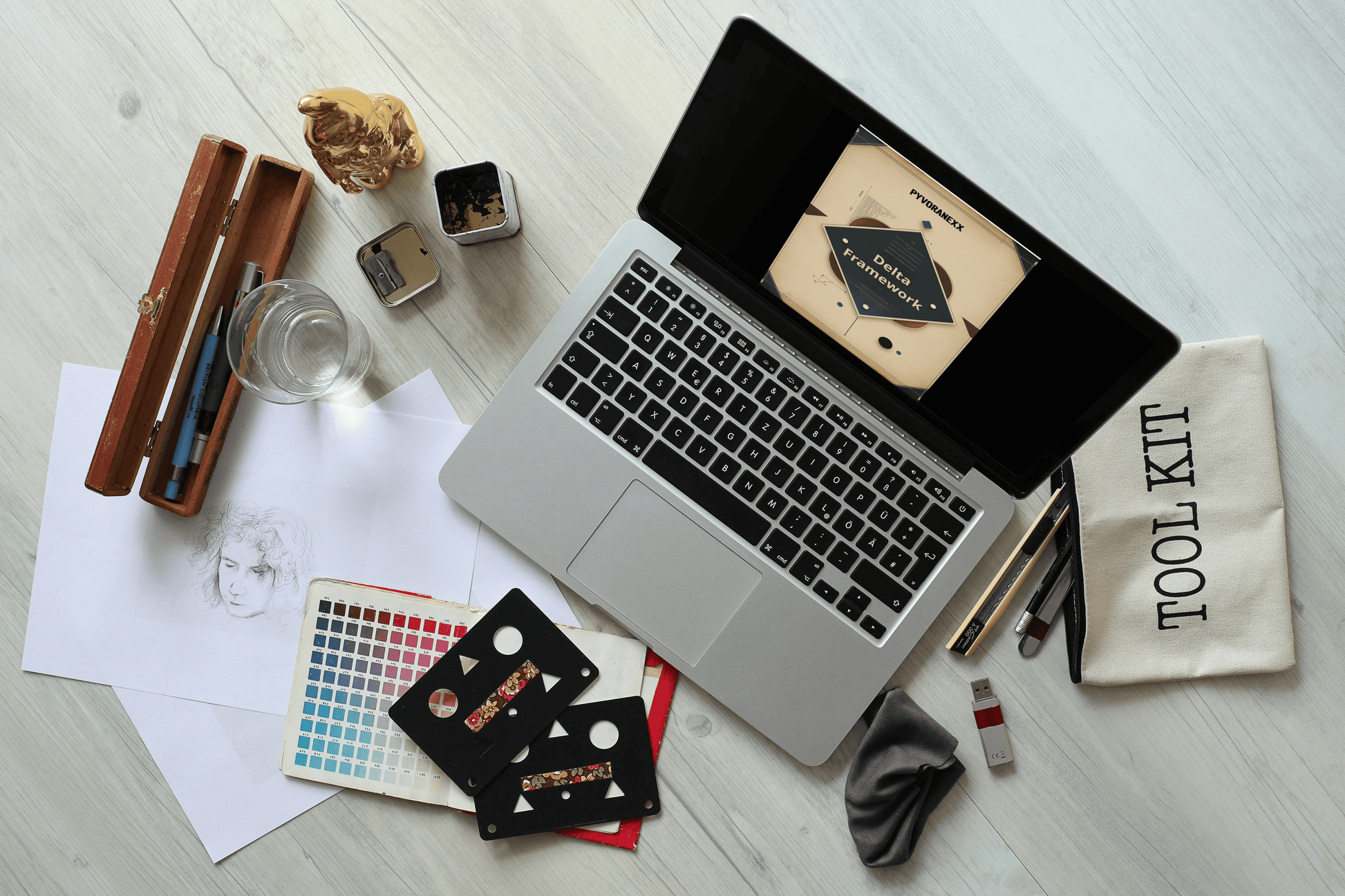 Laptop on a desk with stationery items including a color swatch and a tool kit bag.