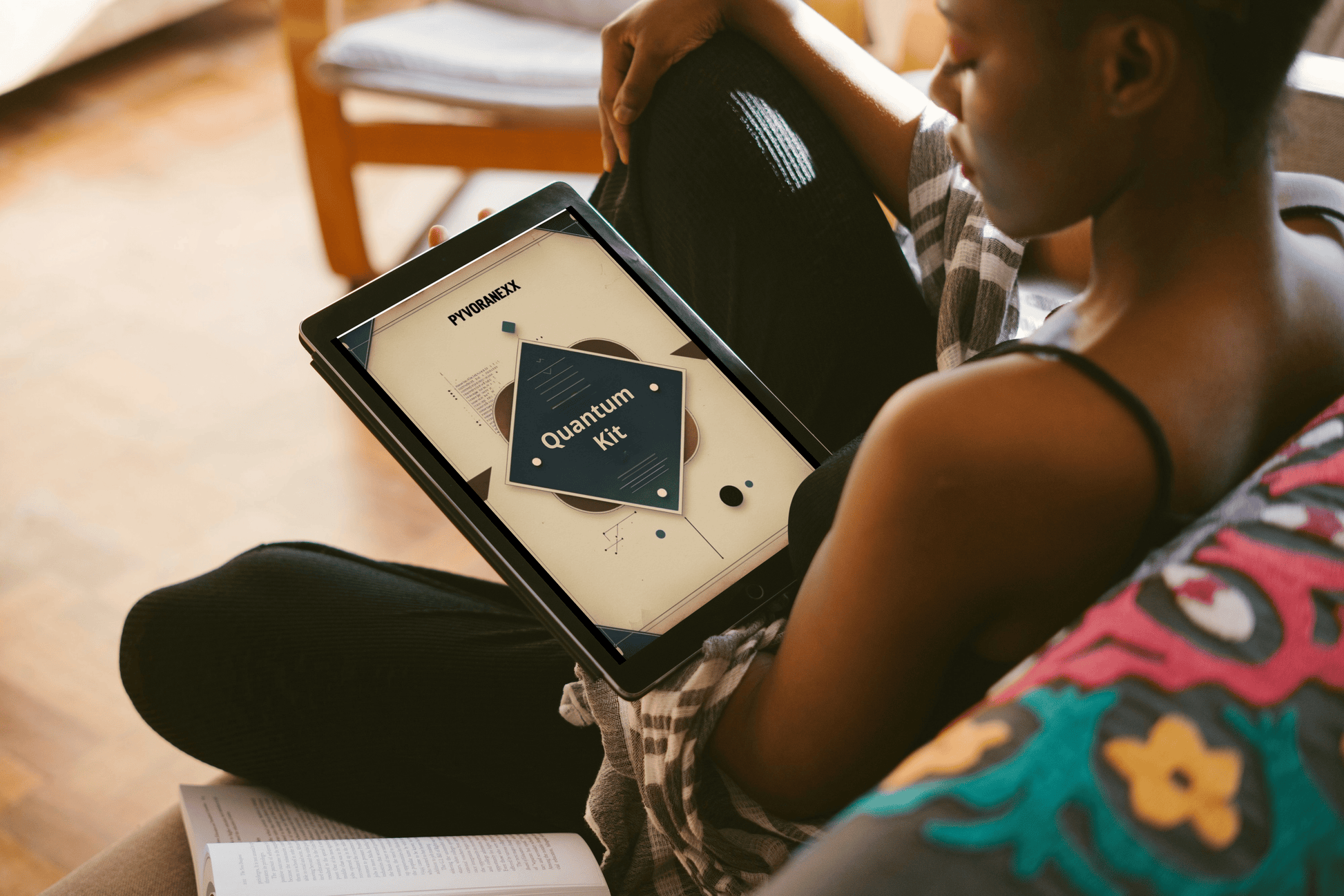 Person holding a Quantum Kit course with a colorful chair and wooden floor in the background