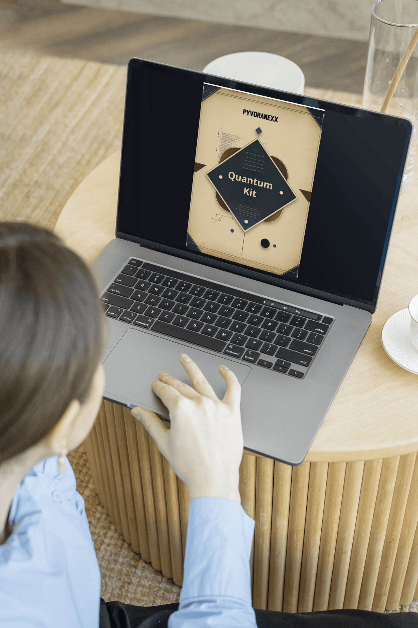 Person using a laptop on a wooden table with a visible brand logo.