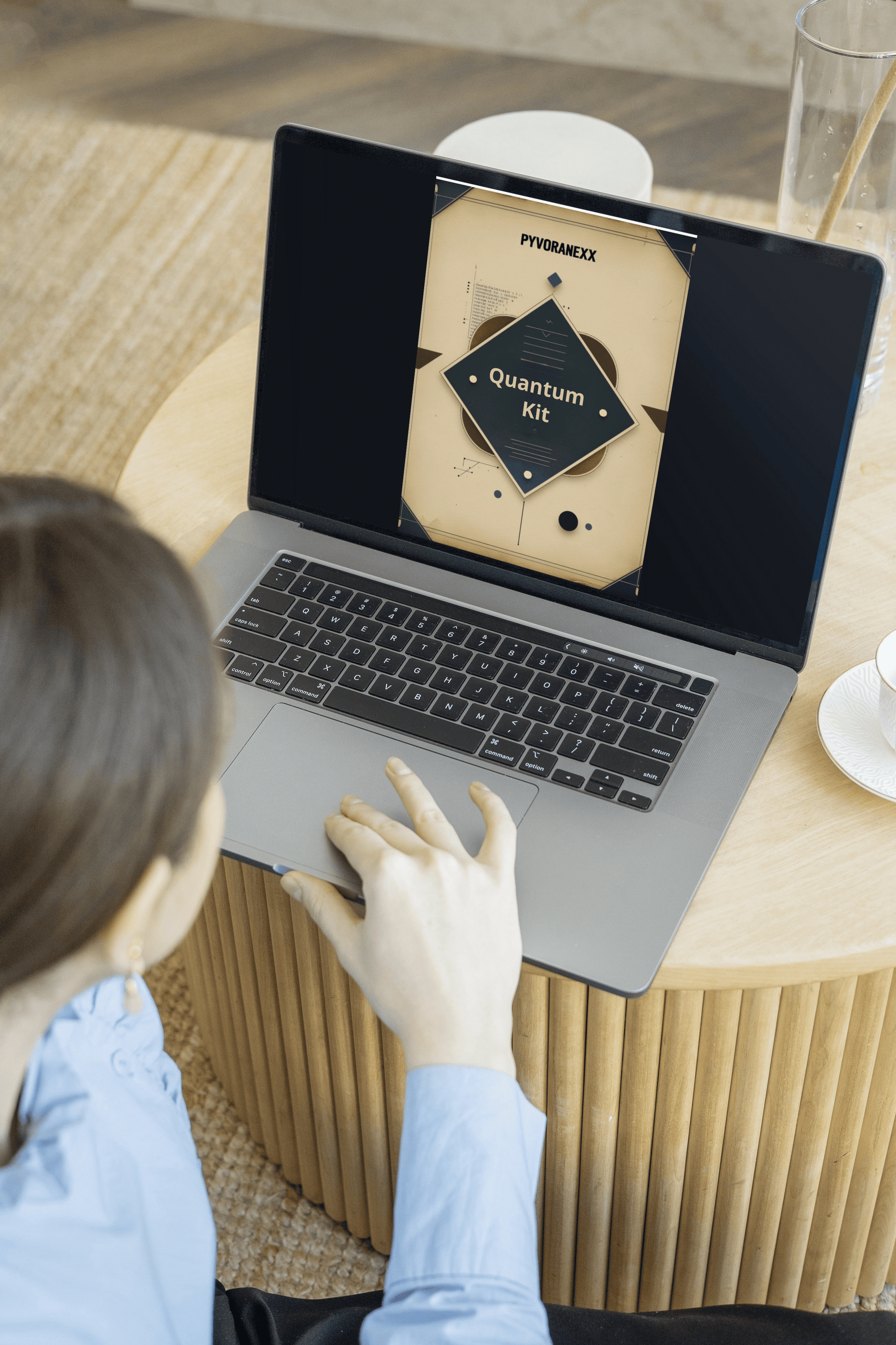 Person using a laptop on a wooden table with a visible brand logo.