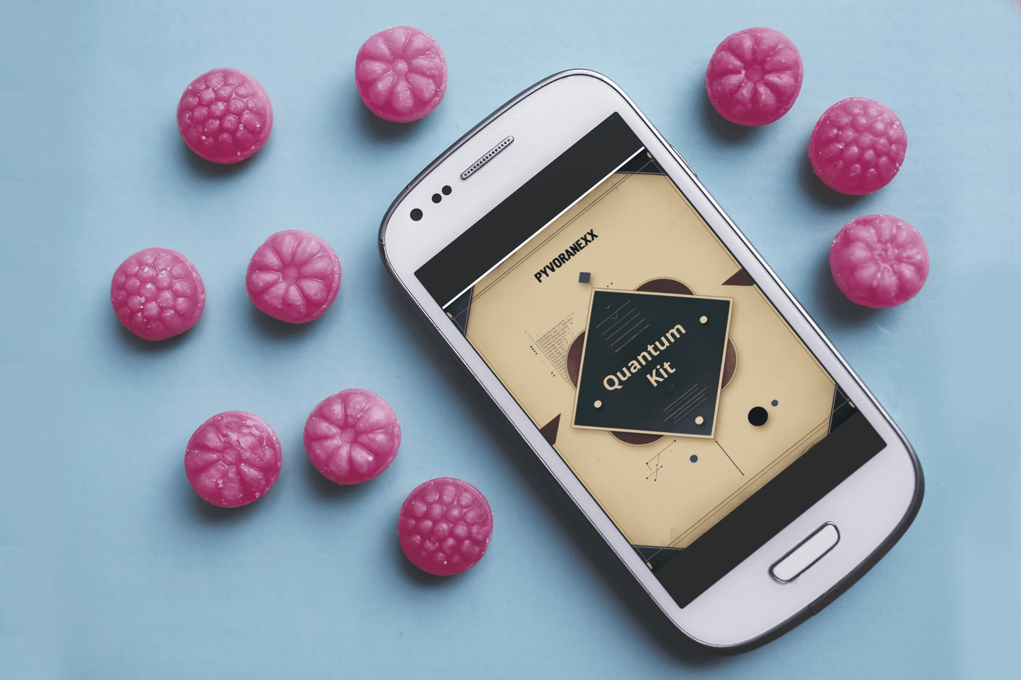 Phone displaying a Quantum Kit course on a blue background with pink spherical objects.